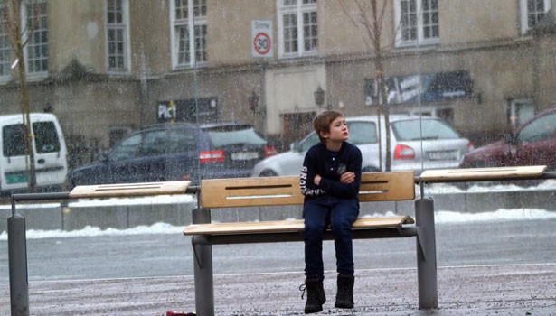 Menino com frio sentado em um banco